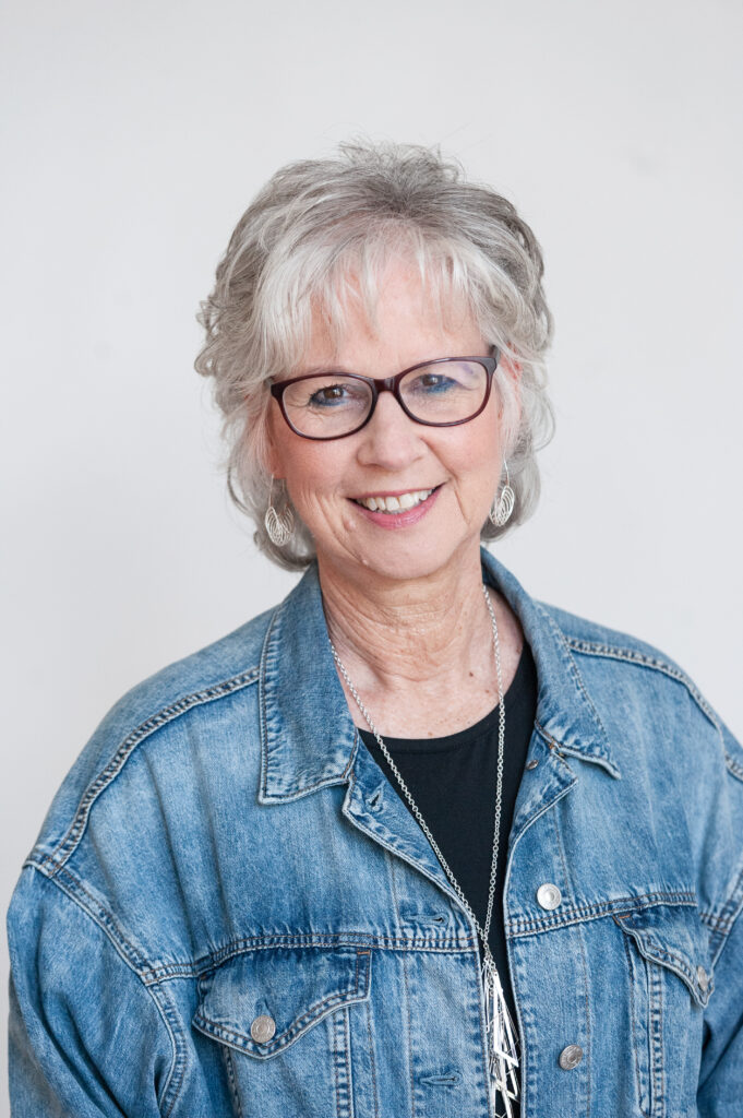 Woman with glasses in a blue denim shirt, smiling